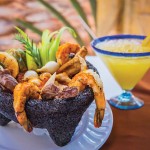 Photo.- page 83 | CaboPictures.com – Caption: The molcajete at Los Barriles features everthing save the kitchen sink (chicken, beef, shrimp, cheese, nopales, and onions).