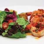 Photo.- page 69 | Arlen Rodriguez – Caption: The Gamberoni Capuleto is a favorite dish af plum shrimp with garlic, olive oil, and parsley that's served with potato salad and a spring mixed salad.