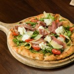 Pizza primavera: ​Neapolitan style pizza with tomato, arugula, Prosciutto di Parma  and Parmigiano Reggiano.