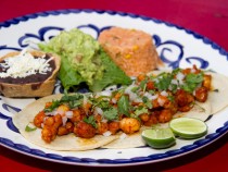 Tacos de Camarón al Pastor.- Shrimp marinated in axiote (annatto) & pineaple adobo, grilled and served in tacos topped with fresh onions and coriander