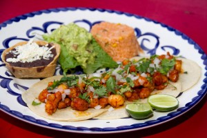 Tacos de Camarón al Pastor.- Shrimp marinated in axiote (annatto) & pineaple adobo, grilled and served in tacos topped with fresh onions and coriander